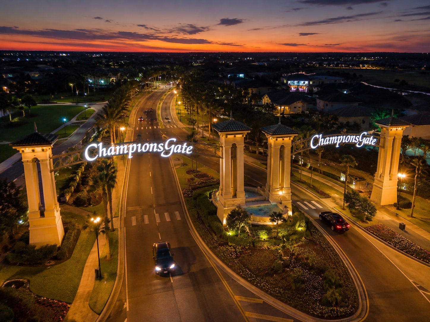 An evening aerial view of the illuminated ChampionsGate entrance and surrounding neighborhood.