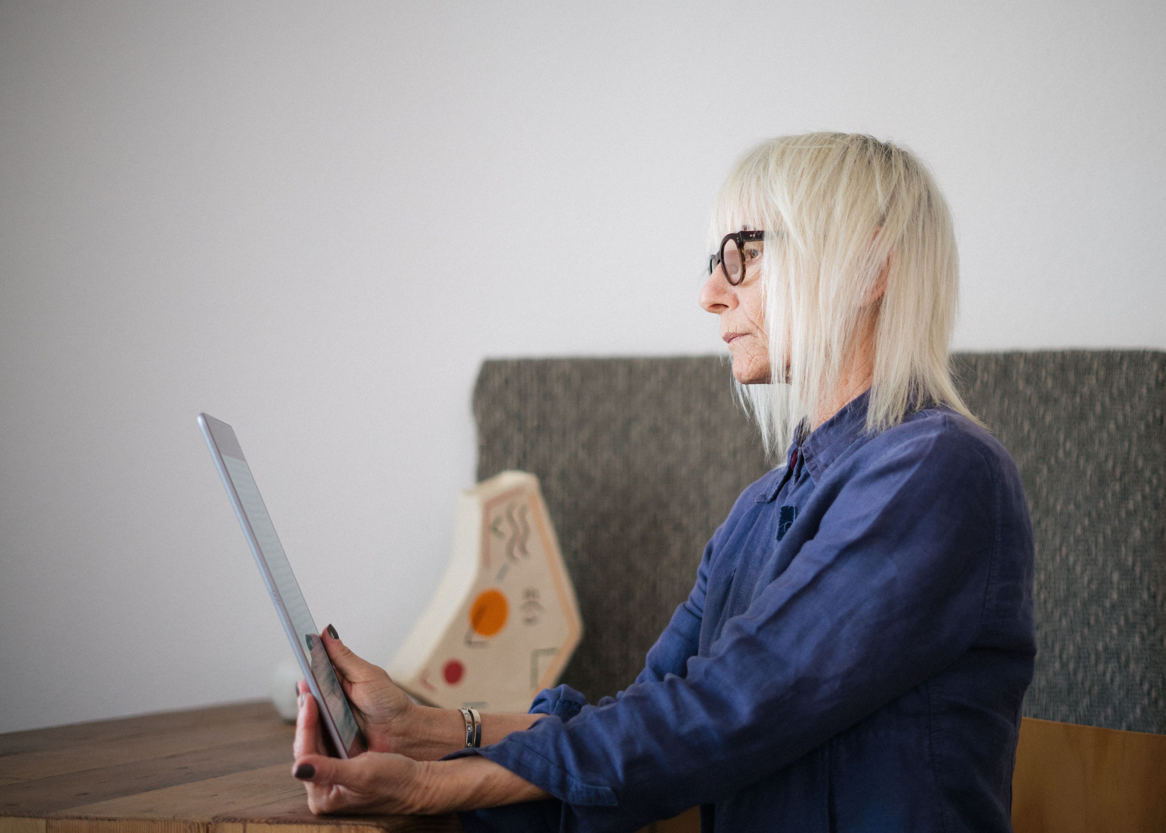 An older woman using a tablet independently at home.
